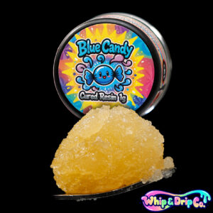 “Whip & Drip Co. Blue Candy cured resin concentrate with golden extract displayed beside blue candy-themed 1 gram product packaging on a black background.”